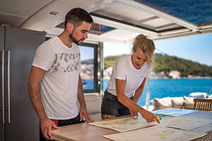 Two People Looking at a Nautical Map on a Sailboat | Sebastus Sailing