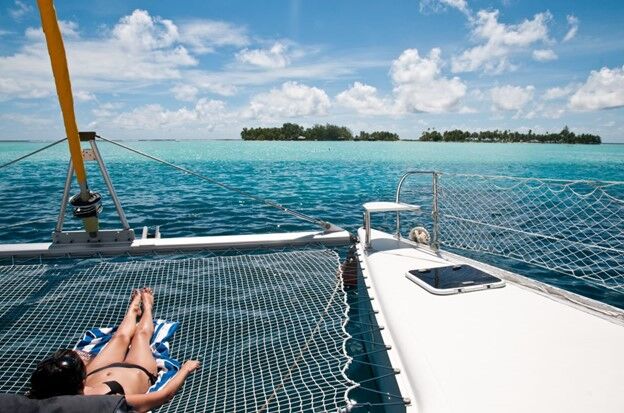 woman relaxing on a catamaran with a view to a small island