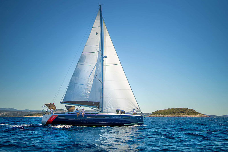 Segelboot mit vollen Segeln und Menschen an der Seite