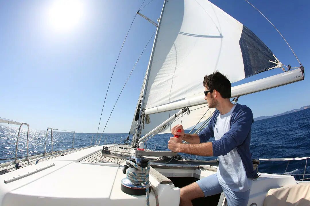 young man using winch on a sailing boat