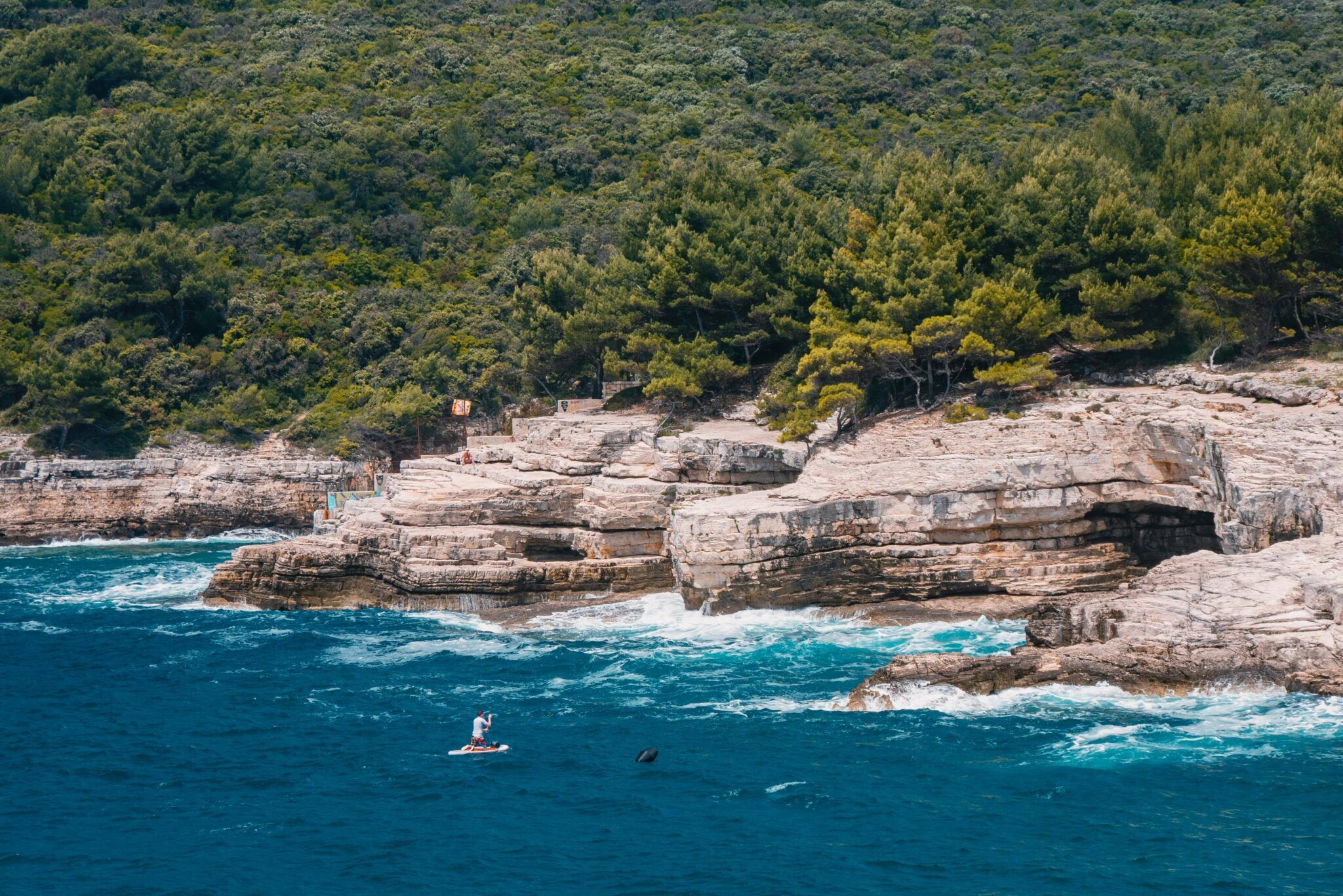 cliffs in Pula with a person on SUP in front