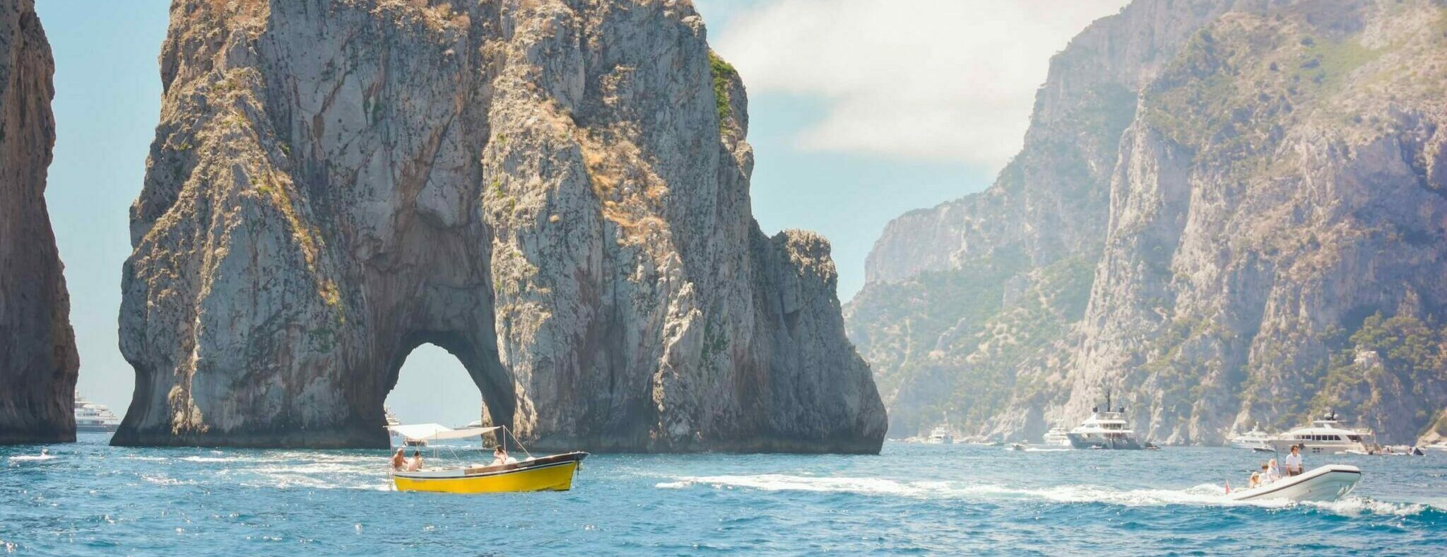 Touristenboote auf dem Wasser vor den Faraglioni-Felsen